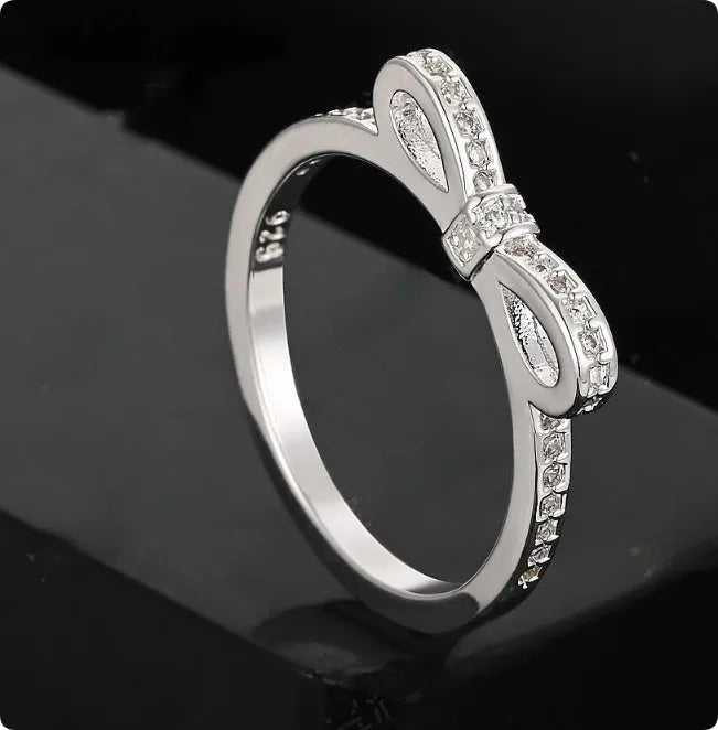 Silver bow-shaped ring with rhinestone and zircon crystal detailing on electroplated metal