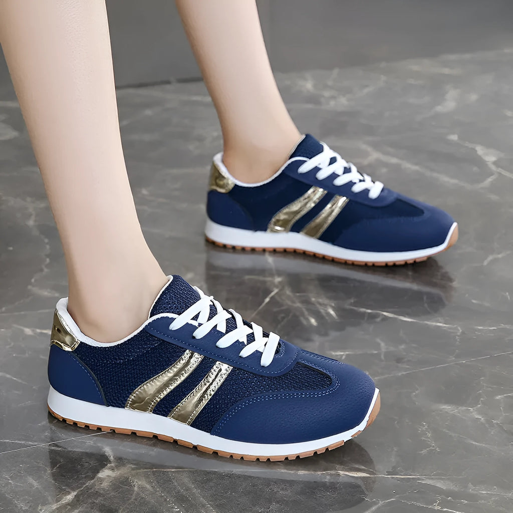 Blue women's casual tennis shoes with cross shoulder straps and white rubber sole on a flat heel.
