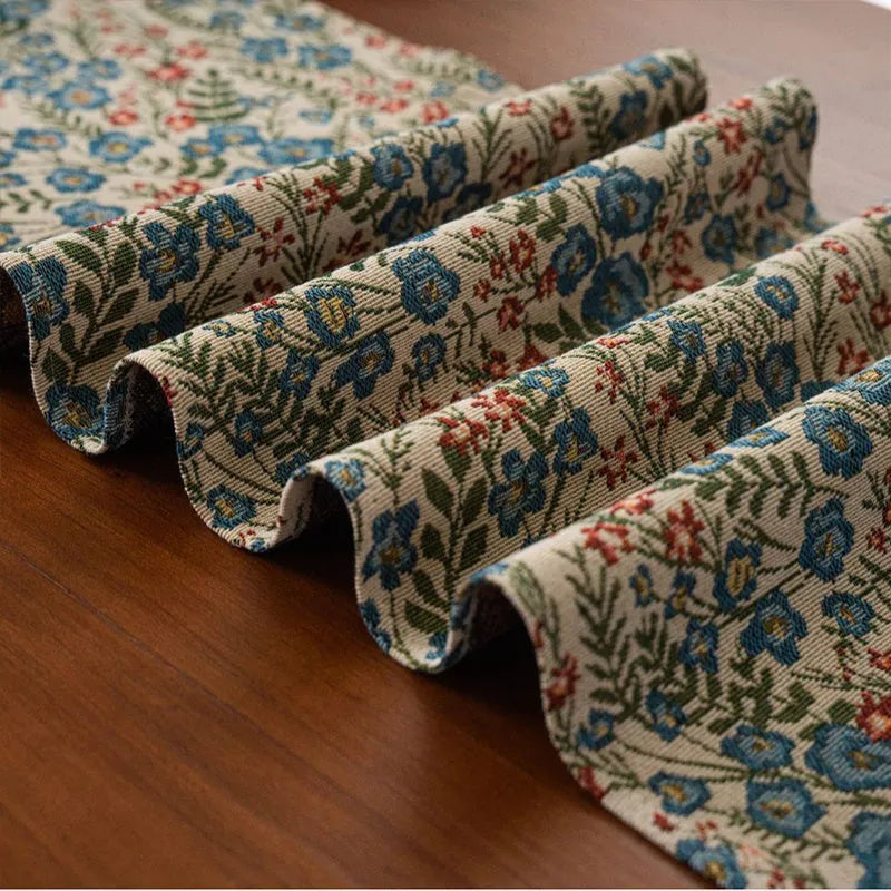 Dark blue Nordic Jacquard table runner with bouquet design and tassels laid on a wooden table.
