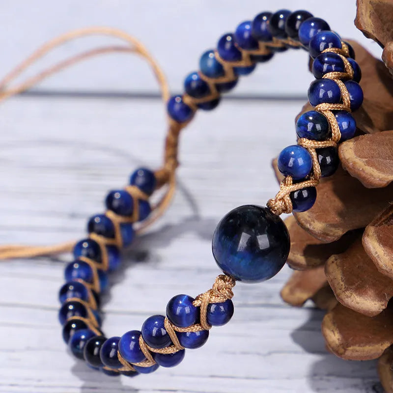 Handwoven geometric pull bracelet made from blue Tigereye stone on a wrist.