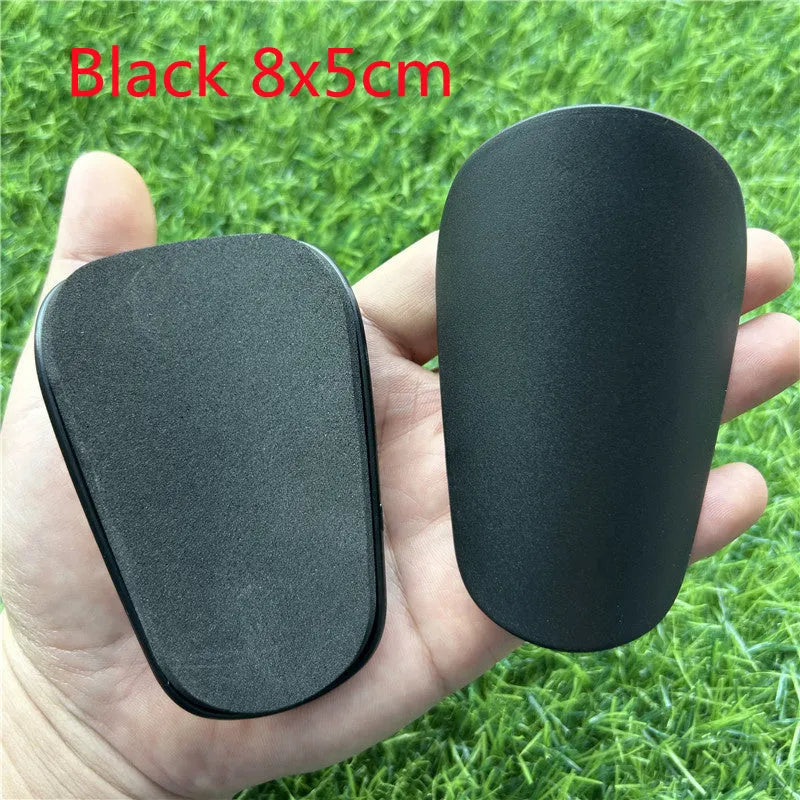 Pair of extra small black and white plastic football shin guards measuring 8x5cm for youth players