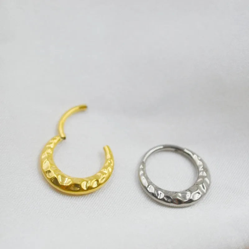 Titanium alloy concave-convex nose ring in gold and silver finishes showing surface texture detail