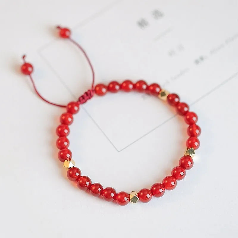 Hand-woven red agate bead bracelet with ethnic design on a wrist.