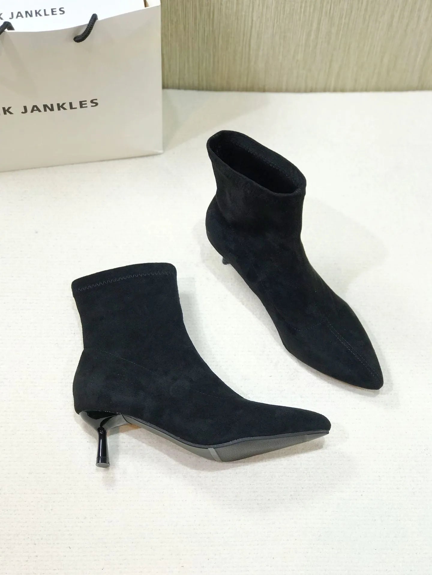 Black pointed toe women's ankle boots with a stiletto heel on a neutral background.