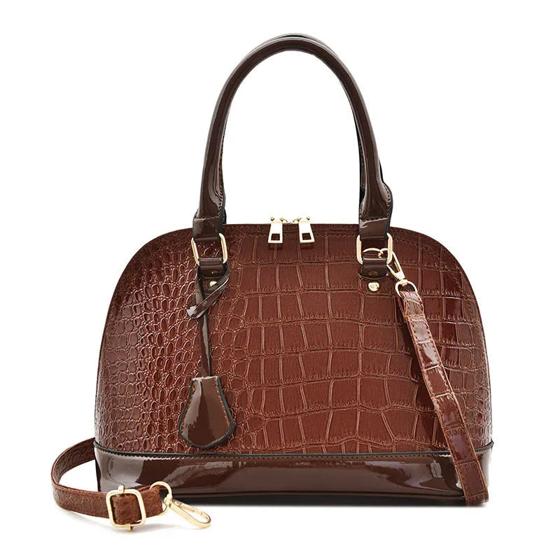 Large shiny PU crossbody shoulder bag in structured shell shape showing black, red, and brown colour options