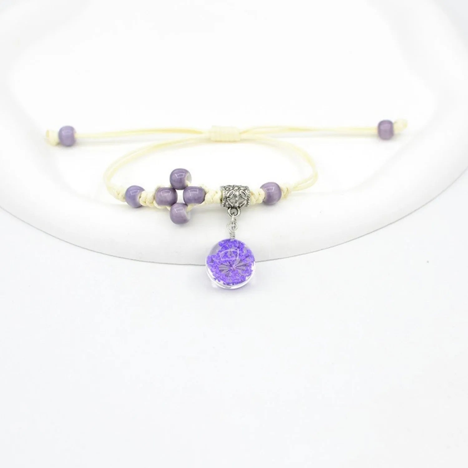 Close-up of a hand-woven glass bracelet with large 1.4 cm beads containing real dried flowers in multiple colour options.