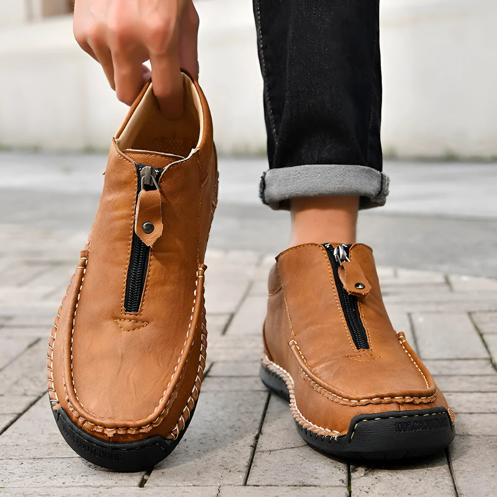 Men's black slip-on loafers with round toe and sewing thread detail on a rubber sole.