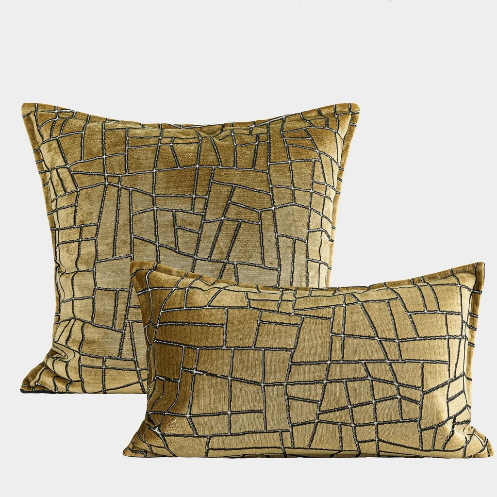 Geometric abstract pattern decorative pillow case in gold colour on a grey sofa.