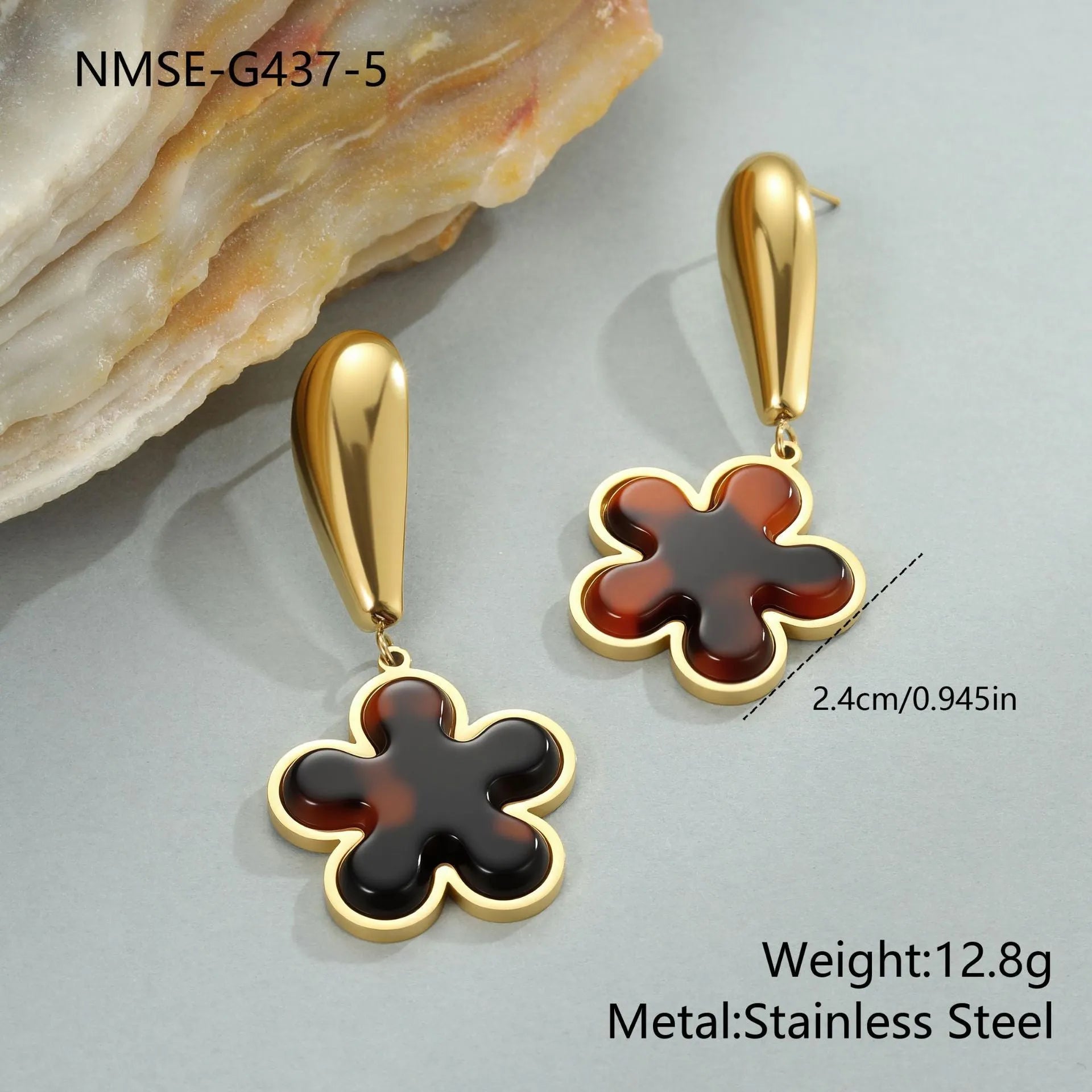 A pair of gold-coloured geometric earrings with a heart shape and a floral design on a white background.