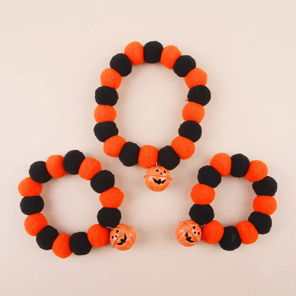 Orange Halloween cat collar with black jack-o'-lantern print and a small detachable fabric pumpkin basket.