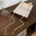 Women's hairpin with pearl, diamond and flower design featuring long tassel detail and gold-coloured grip