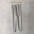 Boy wearing slim straight wool trousers in a neutral colour, showcasing the tapered fit and straight leg opening.