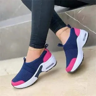 Women's white mesh flat sneakers with a rubber sole shown from the side.