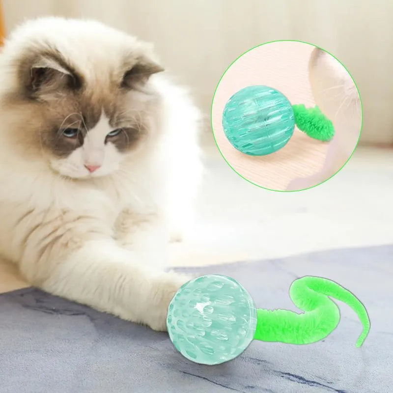 Green interactive cat toy featuring a bouncy ball with a long plush tail on a wooden floor.