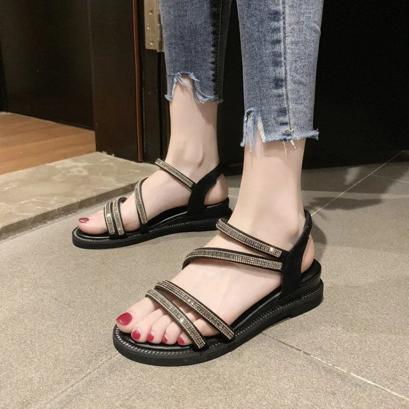 Women's silver flat sandals with rhinestone decoration and elastic strap on a rubber sole.