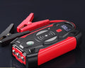 Red portable car jump starter with thick clips and digital display for emergency vehicle battery boosting