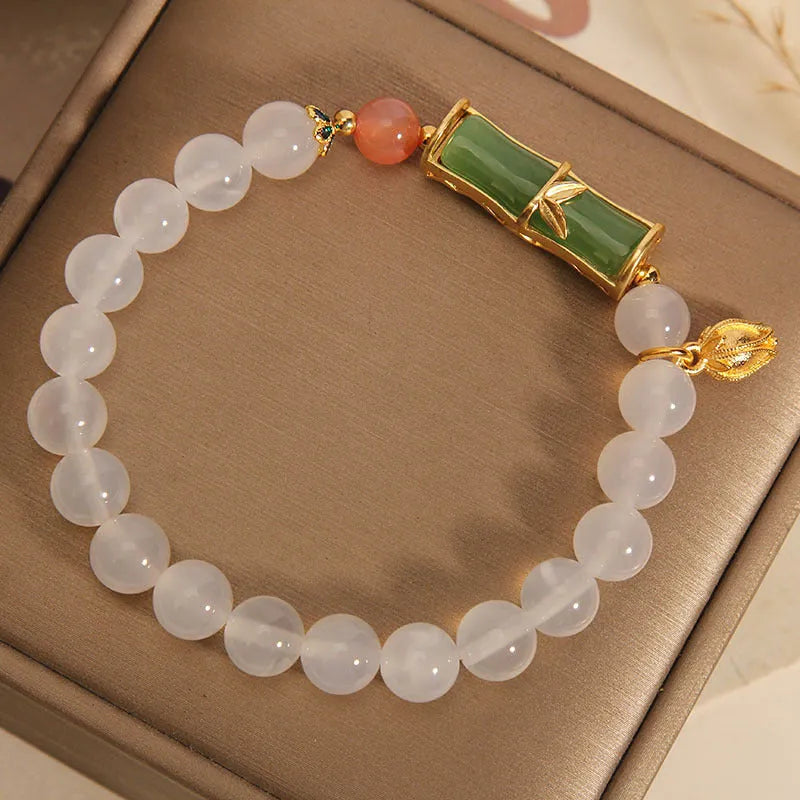 Close-up of a white agate jasper beaded bracelet with a jade bead in a Chinese bamboo style.