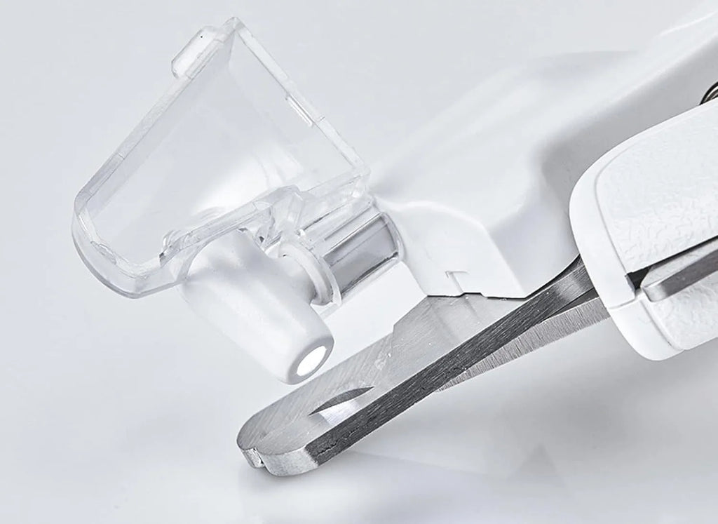 White pet nail clippers with LED light, anti-splash guard, and built-in file on a grey surface