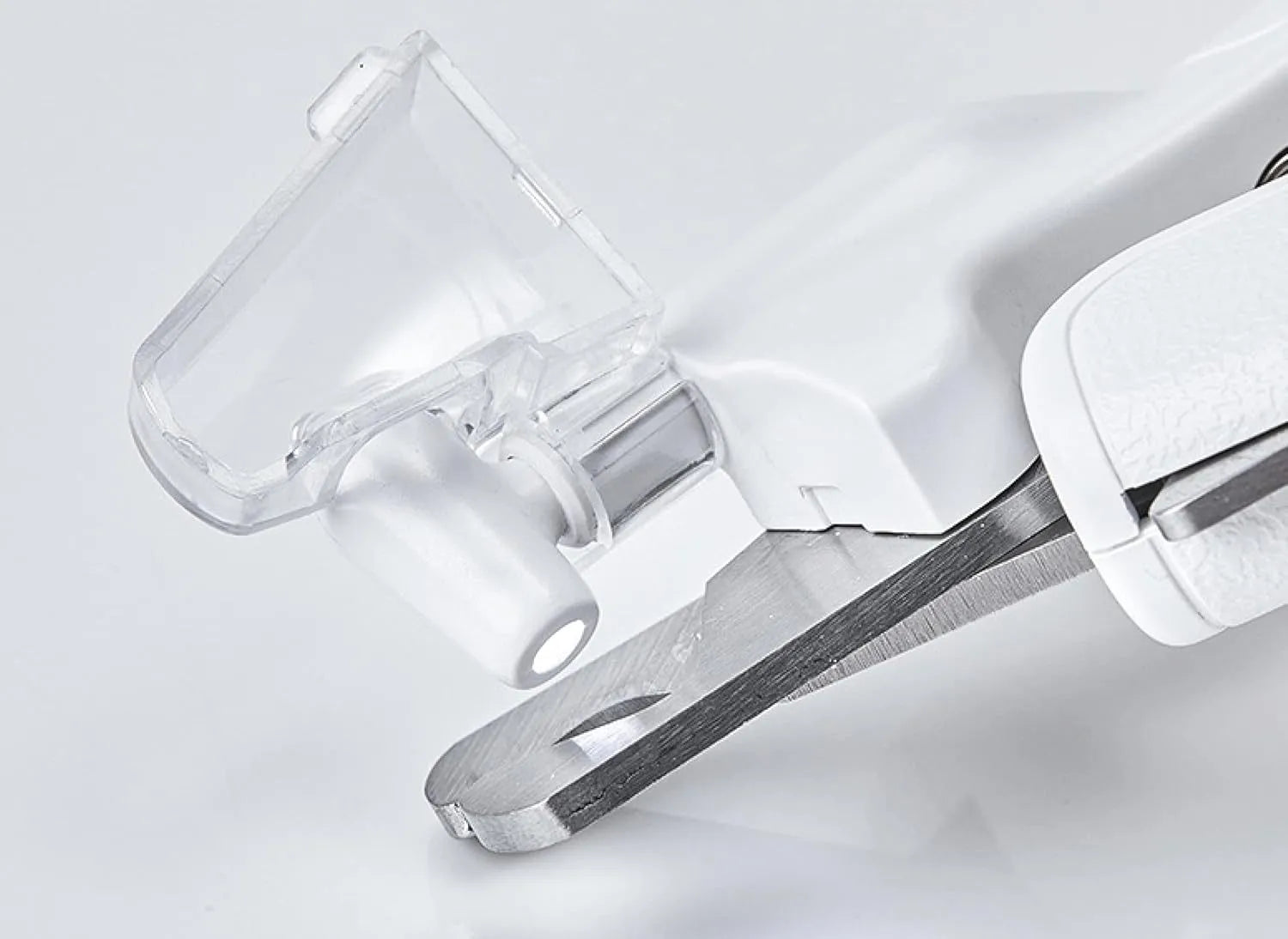 White pet nail clippers with LED light, anti-splash guard, and built-in file on a grey surface