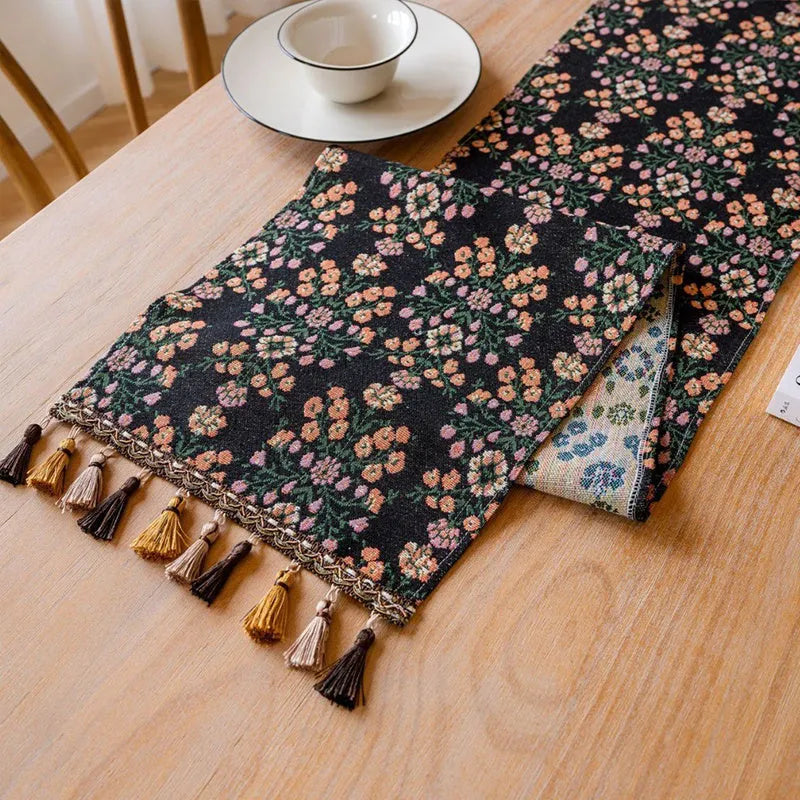 Dark blue Nordic Jacquard table runner with bouquet design and tassels laid on a wooden table.