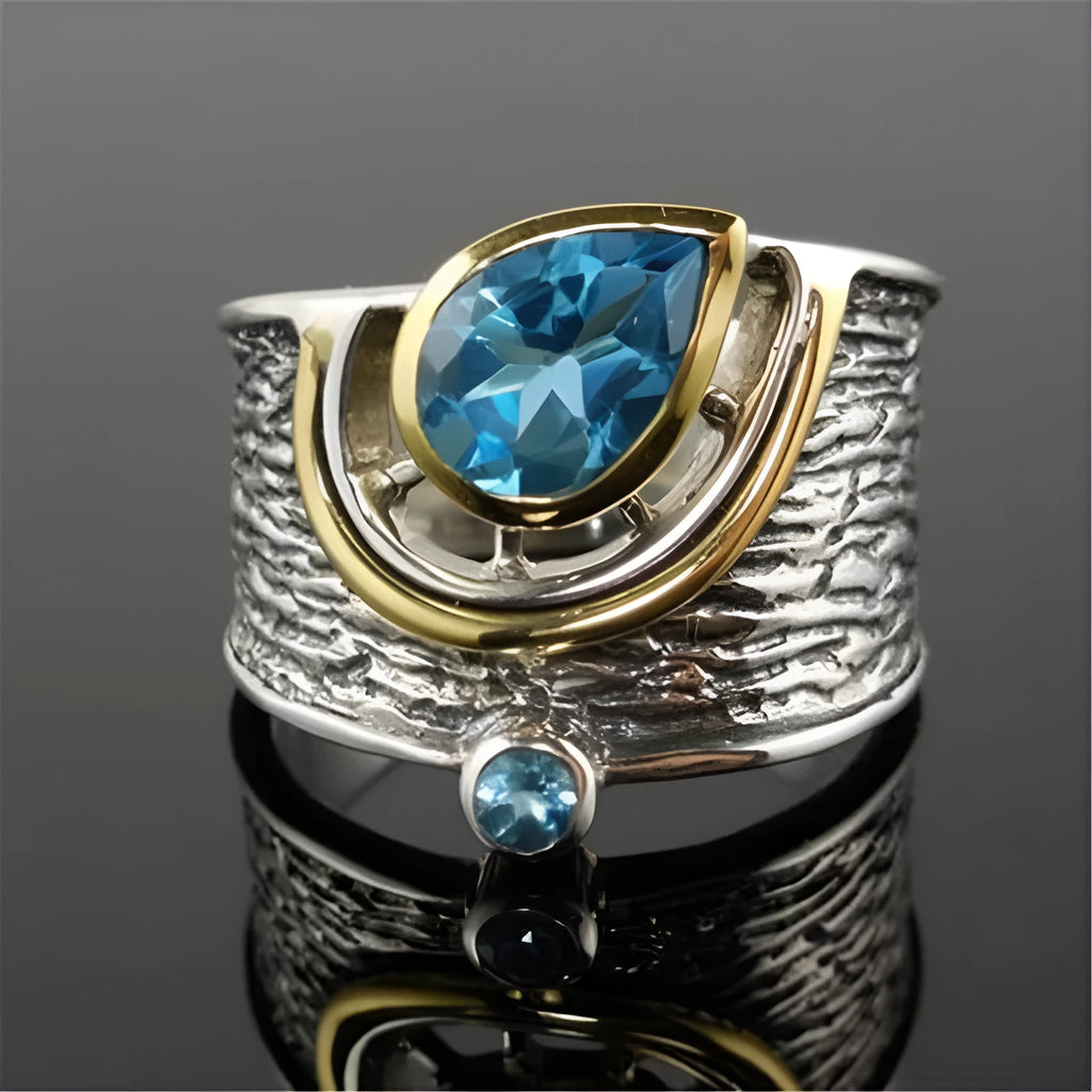 Blue zircon drop shape ring with Chinese style inlaid design on alloy band.