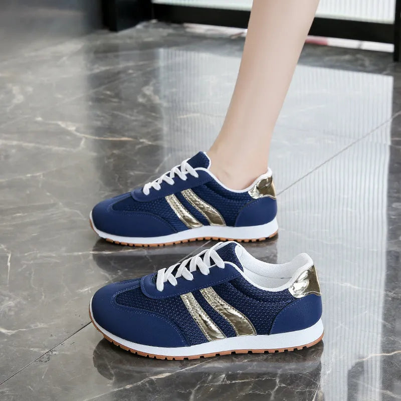 Blue women's casual tennis shoes with cross shoulder straps and white rubber sole on a flat heel.