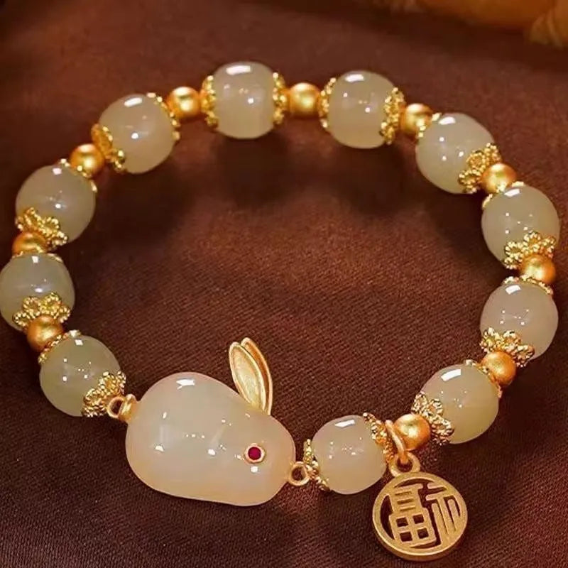 Green jade women's bracelet with a sculpted hare charm, engraved Fu character, and lily detailing
