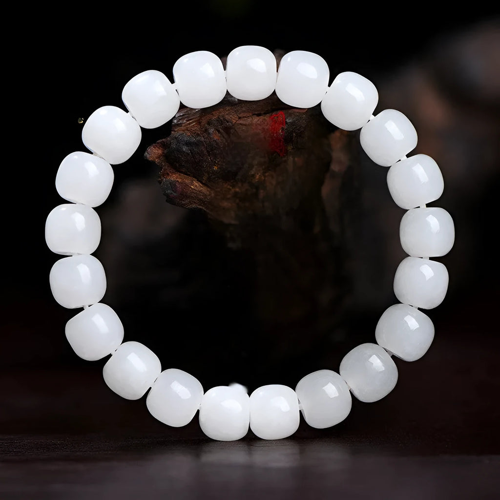 White Hetian jade barrel bead bracelet for men and women on a plain background.