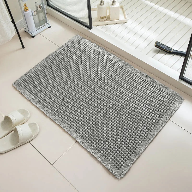 Modern checkered pattern absorbent non-slip bathroom floor mat in a neutral colour on tiled floor.