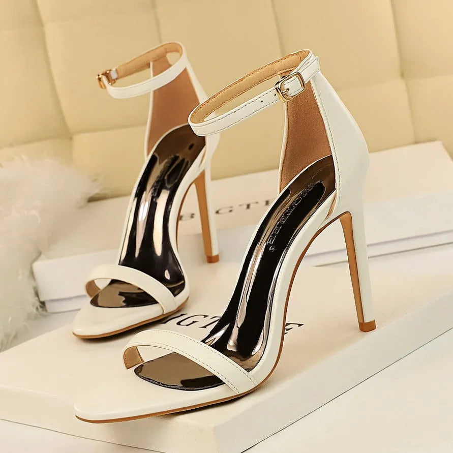 Women's open toe high heels with an ankle strap and buckle closure in a solid colour.