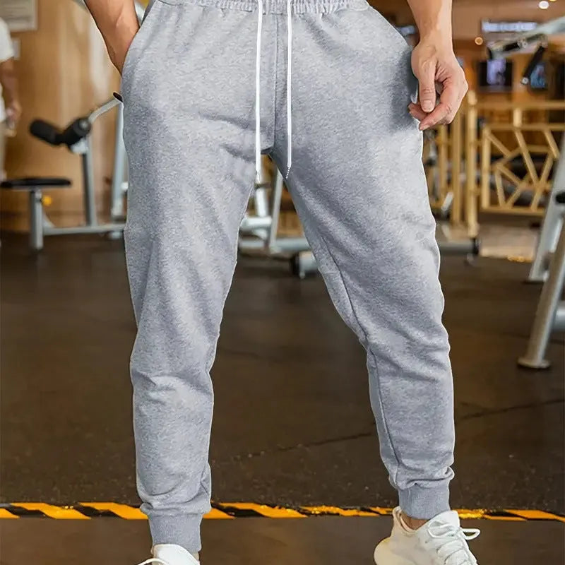 Men's loose-fit casual trousers with an elastic drawstring waist in a neutral colour.