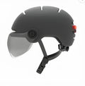 Adult cycling helmet with a red LED brake light integrated into the tail, shown in two style variants.