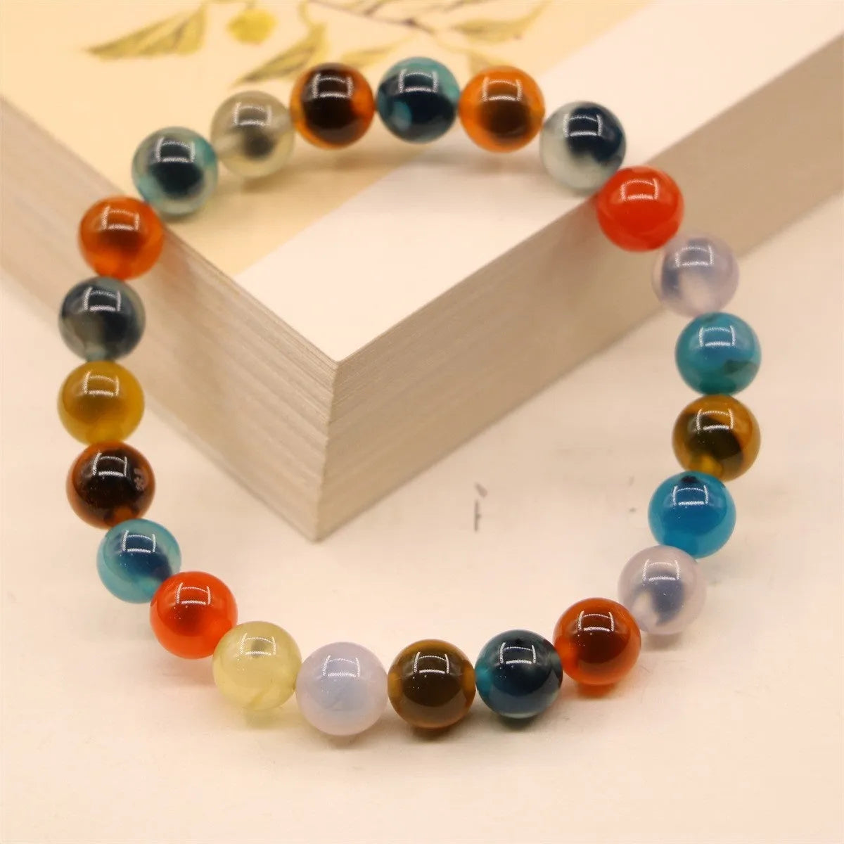 Close-up of a women's snake chain bracelet with colourful agate hearts and detailed copper coins.