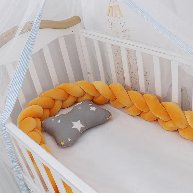 Bendable braid-knot baby crib bumper in spandex velvet, shown in a light grey colour wrapped around a cot.