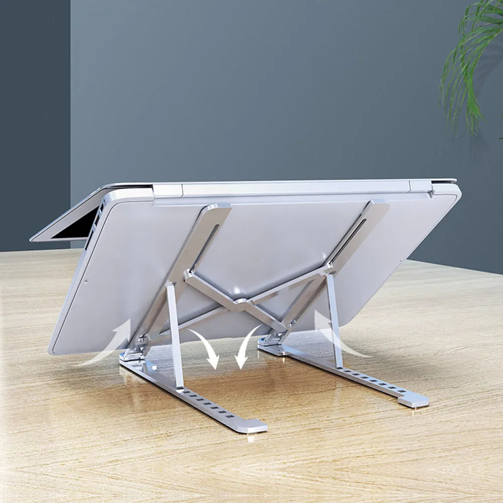 Silver foldable aluminium laptop stand holding a MacBook at an angle, shown next to a backpack.
