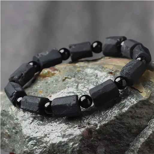 Black tourmaline rough stone bracelet with unpolished beads on a wrist.