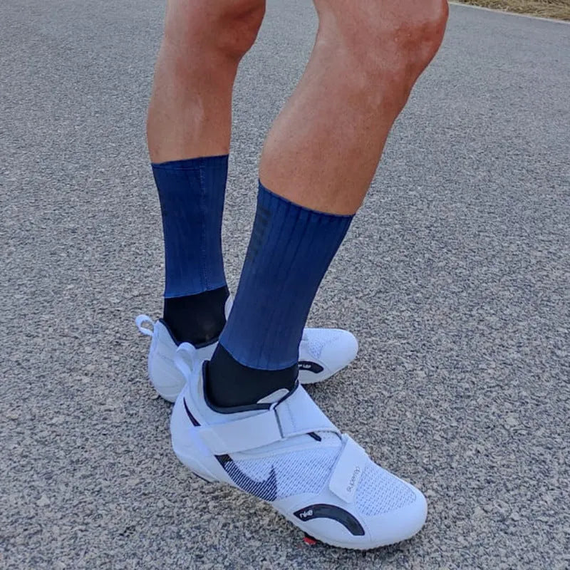 Pair of breathable athletic socks for running and cycling in orange colour on a grey background
