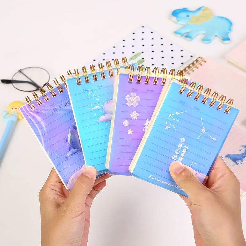 Set of four A7 spiral notebooks with different coloured covers showing constellation, cherry blossom, ocean, and universe designs.