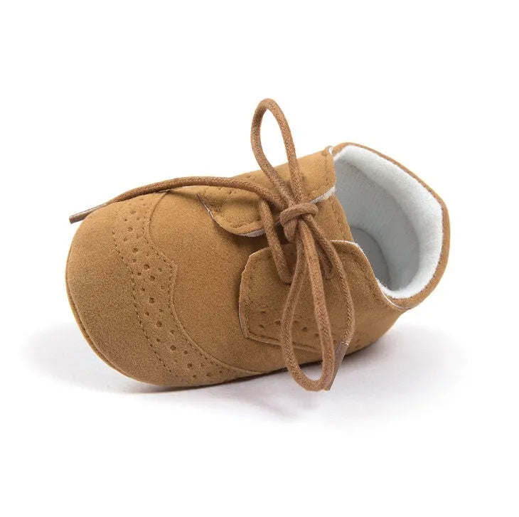 Vintage baby shoes with soft soles in light brown colour showing synthetic leather upper
