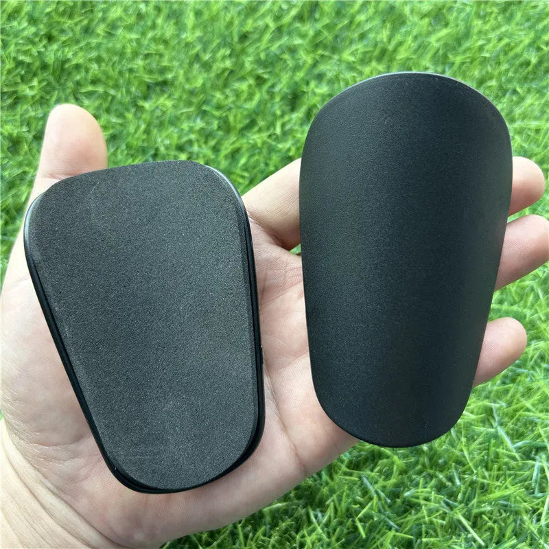 Pair of extra small black and white plastic football shin guards measuring 8x5cm for youth players