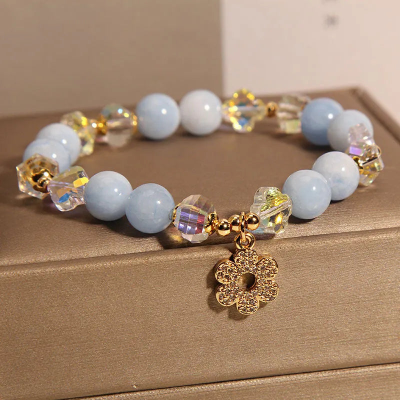 Women's aquamarine crystal four-leaf clover bracelet with pearl accents on a silver chain.