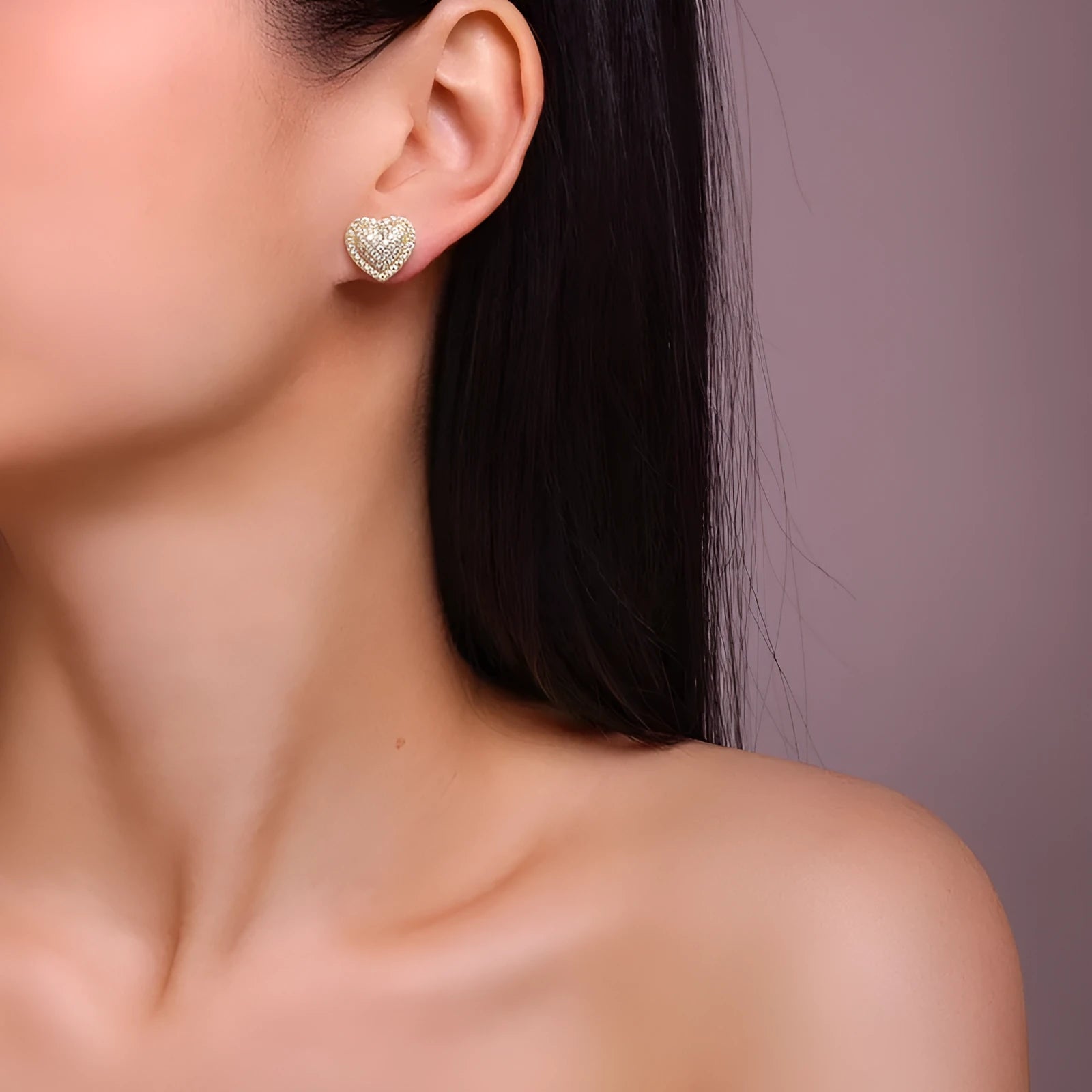 A pair of golden-colour heart stud earrings with a central moissanite stone, on a silver background.