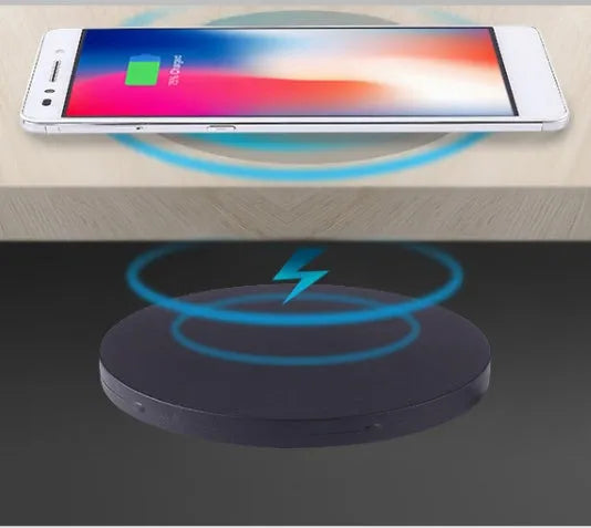 Round hidden wireless charger for embedding in desks, compatible with iPhone and Samsung phones.