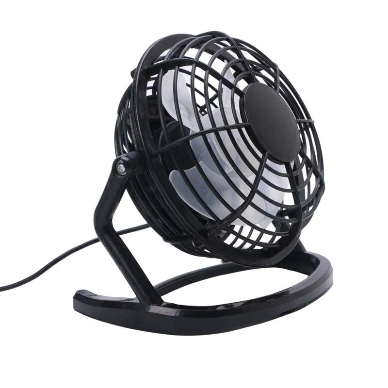 Black mini USB desk fan with adjustable head on a wooden desk next to a laptop.