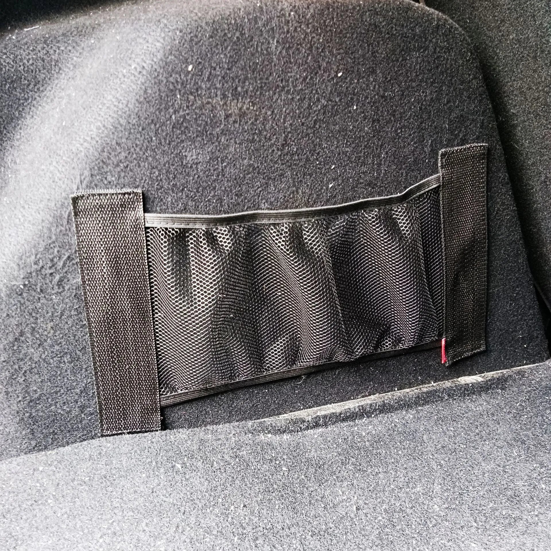Elastic car boot storage net organiser holding various loose items securely in place