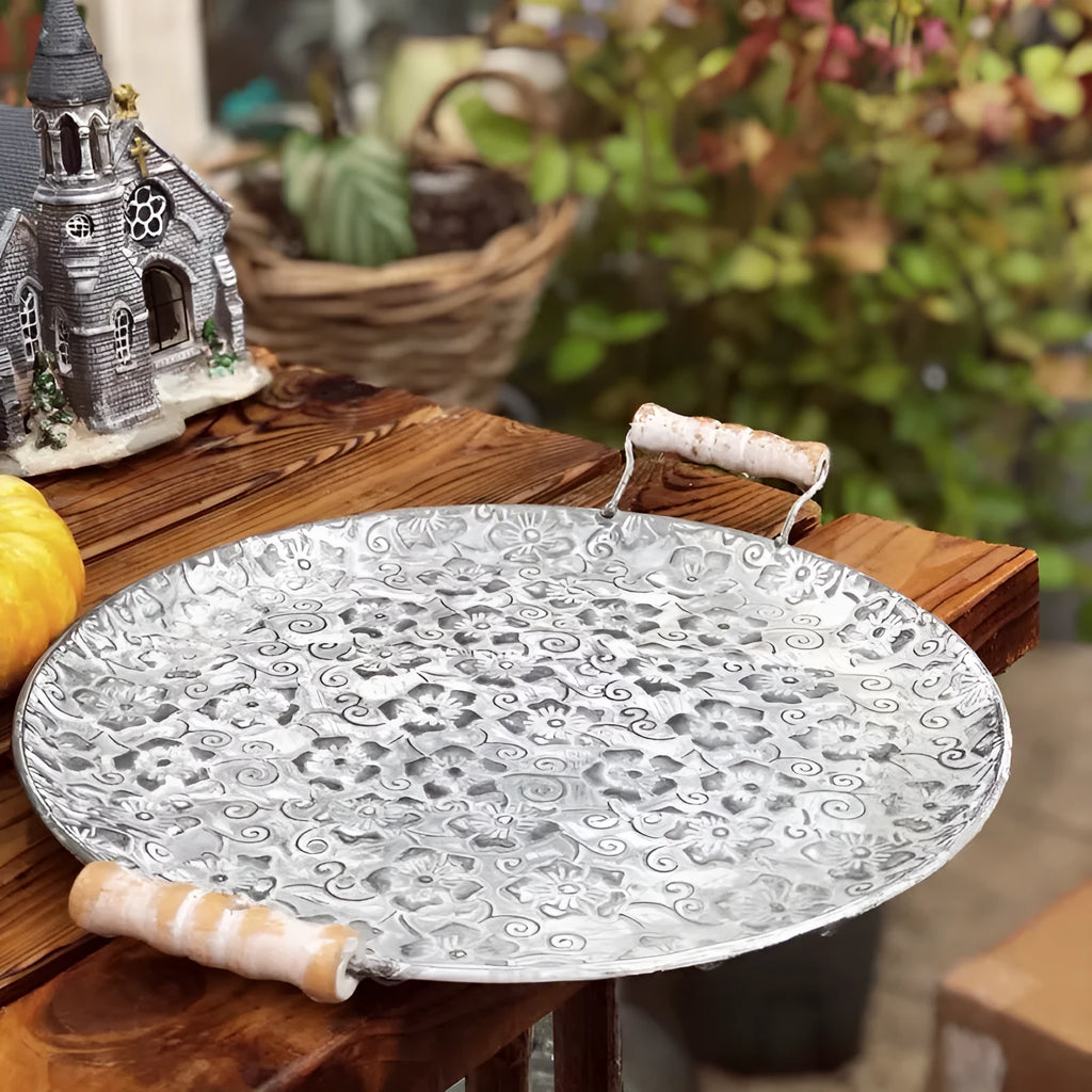 Round wrought iron storage tray in a classic metal colour on a wooden surface.