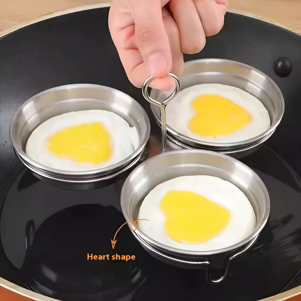 Compact stainless steel heart-shaped electric egg steamer on a kitchen counter.