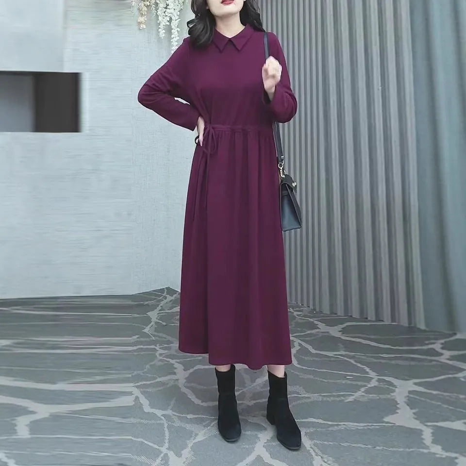 Purplish red plus size long sleeve dress for women with a long skirt, shown on a hanger.
