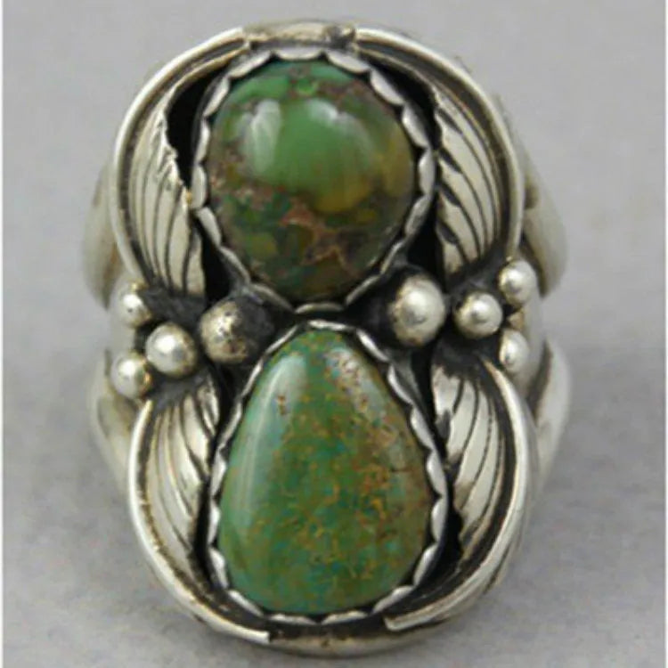 Close-up of a women's geometric turquoise ring with a retro inlaid design on a finger.