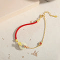 Women's red rope bracelet with silver and gold peace buckle charm featuring koi fish design